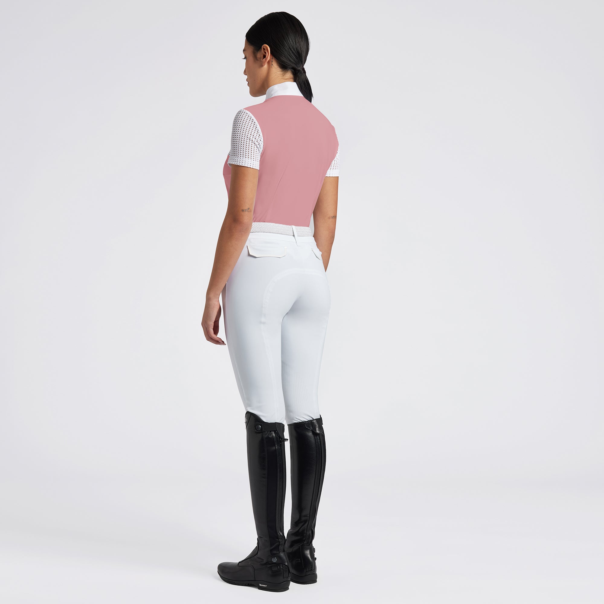 Highlight the Cavalleria Toscana Short Sleeve Perforated Jacquard Zip Competition Shirt through a variety of images that showcase its breathable fabric and sleek design. Include close-up shots of the perforated jacquard material and the zip closure, as well as action shots that demonstrate the shirt’s performance in an equestrian setting. Focus on the short sleeve design and the tailored fit, emphasizing both style and functionality.