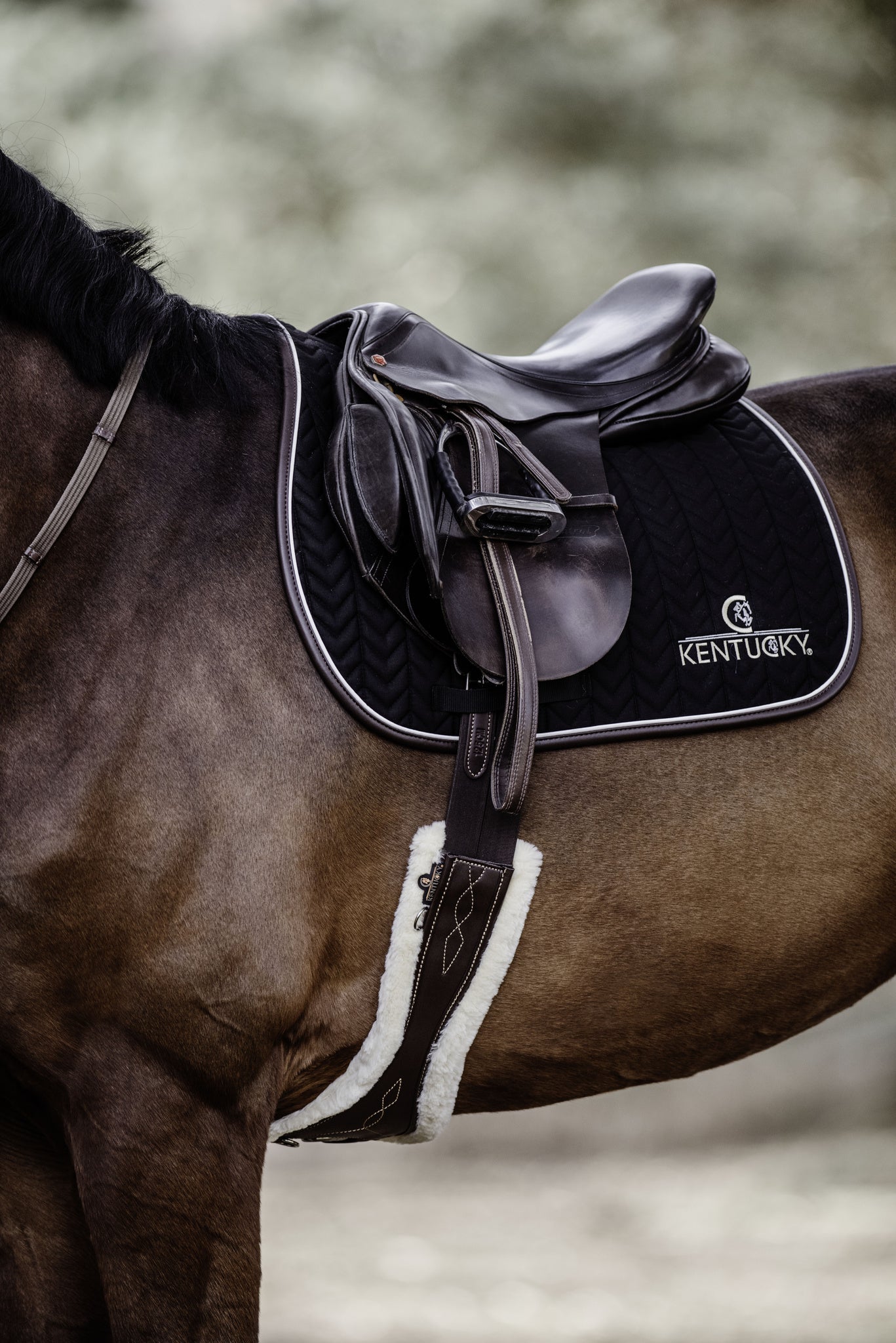 Our Saddle Pad Leather Fishbone is shaped for jumping and provides excellent cushioning between the horse’s back and the saddle while protecting against friction. This saddle pad has a unique fishbone quilting. It has no annoying straps to attach to the saddle, only a nylon strap for the girth. The Saddle Pad Leather Fishbone features a very classy leather binding and the stylish Kentucky logo