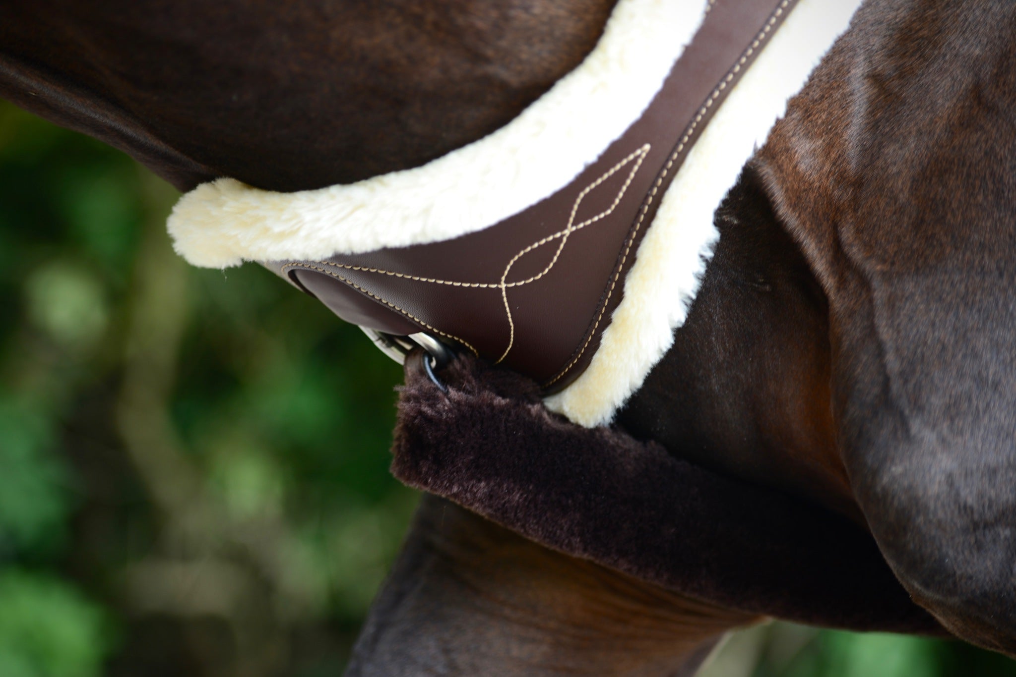 The Kentucky anatomical girth with sheepskin lining. This girth is made from artificial leather, making it softer, more durable and easier to maintain and clean. The faux sheepskin is removable, making it easier to watch and re attaches with strong Velcro. A silver hope and carabiner is found underneath to attach your martingale, breastplate, draw reigns etc. The girth is available in black or brown.
