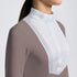 Close-up of a woman wearing a fitted long-sleeve equestrian-style top with a high mock neck. The garment is taupe brown with a contrasting white yoke panel featuring subtle vertical pleats and a small embroidered logo on the collar.