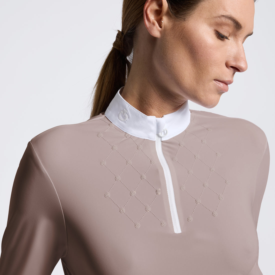 Close-up of a woman wearing a sheer taupe long-sleeve top with a contrasting white mock neck collar and white button placket, featuring delicate chain embroidery on the chest.