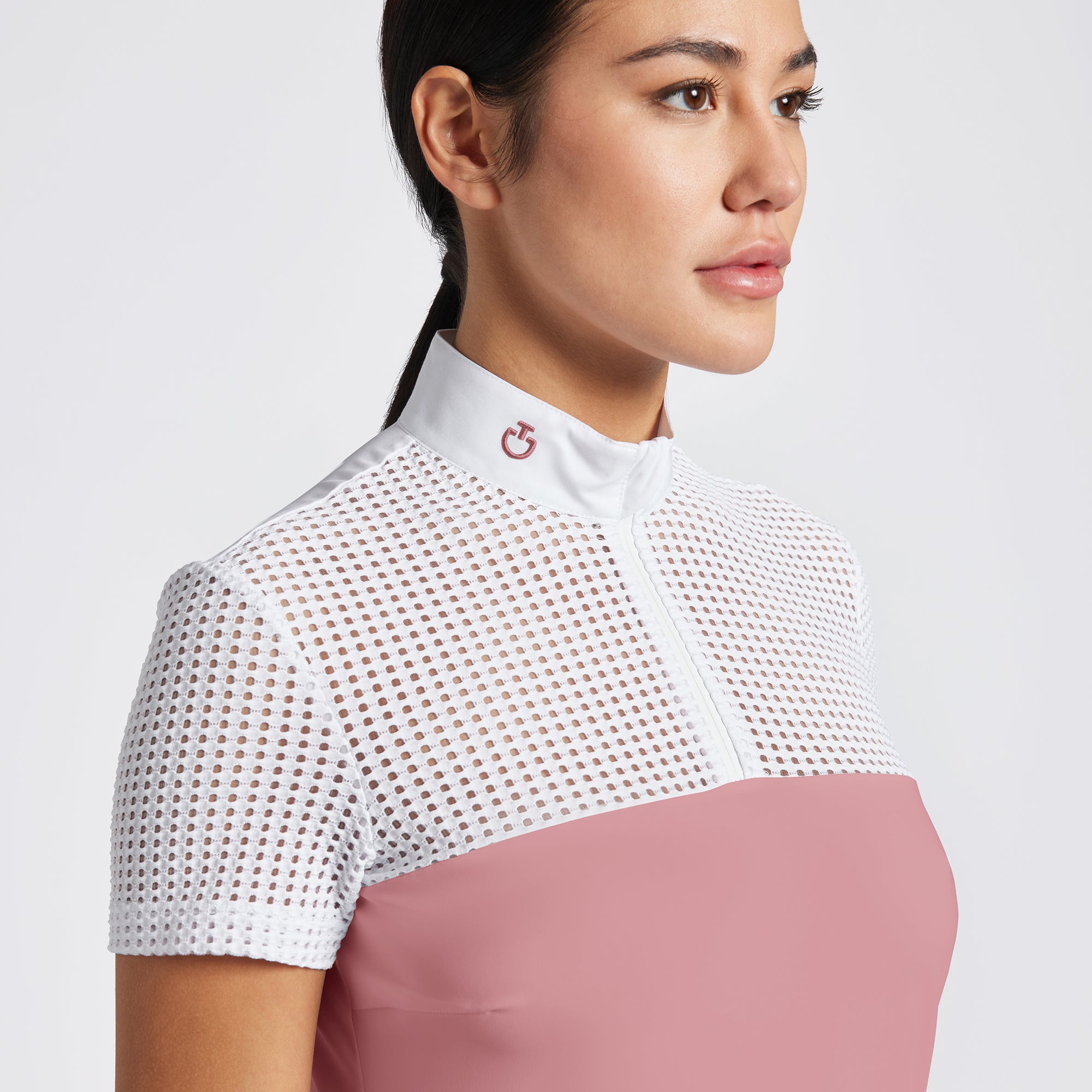 Highlight the Cavalleria Toscana Short Sleeve Perforated Jacquard Zip Competition Shirt through a variety of images that showcase its breathable fabric and sleek design. Include close-up shots of the perforated jacquard material and the zip closure, as well as action shots that demonstrate the shirt’s performance in an equestrian setting. Focus on the short sleeve design and the tailored fit, emphasizing both style and functionality.