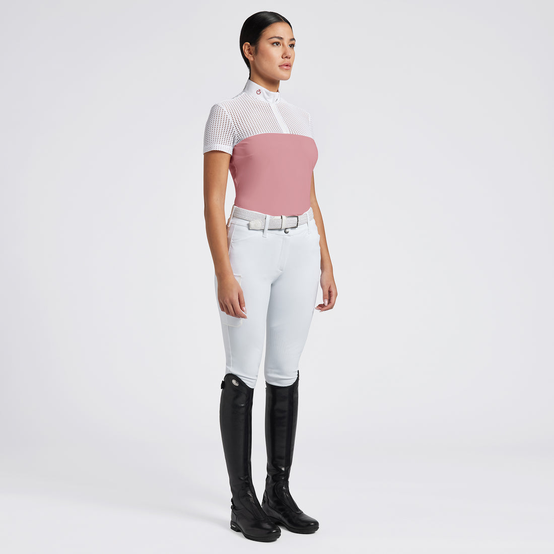 Highlight the Cavalleria Toscana Short Sleeve Perforated Jacquard Zip Competition Shirt through a variety of images that showcase its breathable fabric and sleek design. Include close-up shots of the perforated jacquard material and the zip closure, as well as action shots that demonstrate the shirt’s performance in an equestrian setting. Focus on the short sleeve design and the tailored fit, emphasizing both style and functionality.

