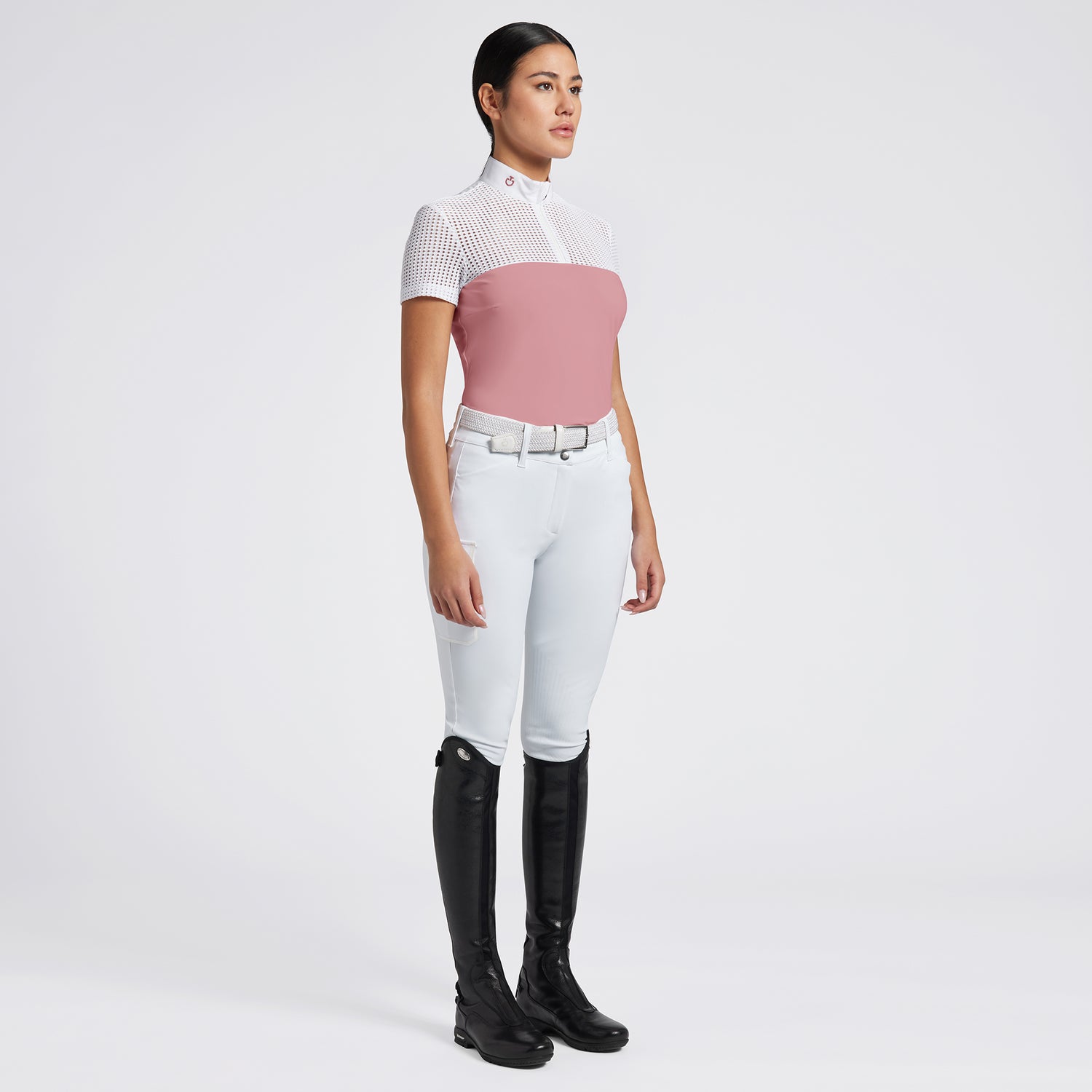 Highlight the Cavalleria Toscana Short Sleeve Perforated Jacquard Zip Competition Shirt through a variety of images that showcase its breathable fabric and sleek design. Include close-up shots of the perforated jacquard material and the zip closure, as well as action shots that demonstrate the shirt’s performance in an equestrian setting. Focus on the short sleeve design and the tailored fit, emphasizing both style and functionality.

