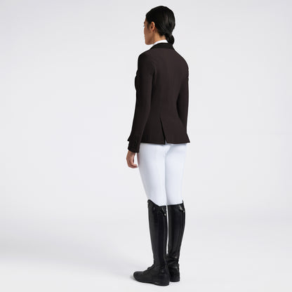 A woman shown from the back wearing a dark brown equestrian jacket, white breeches, and black riding boots against a light gray studio background.