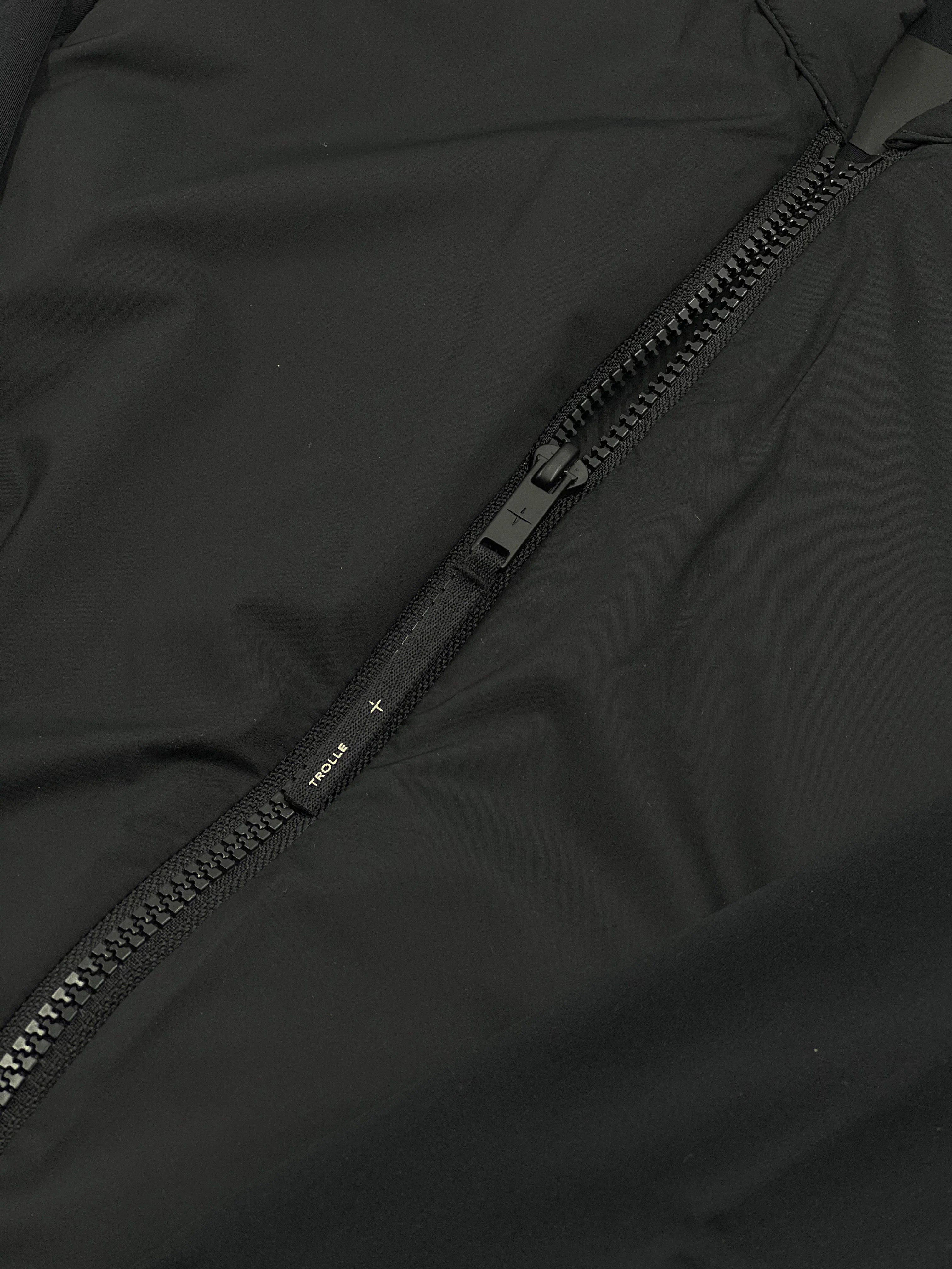 Close-up of a black jacket zipper with a brand logo.