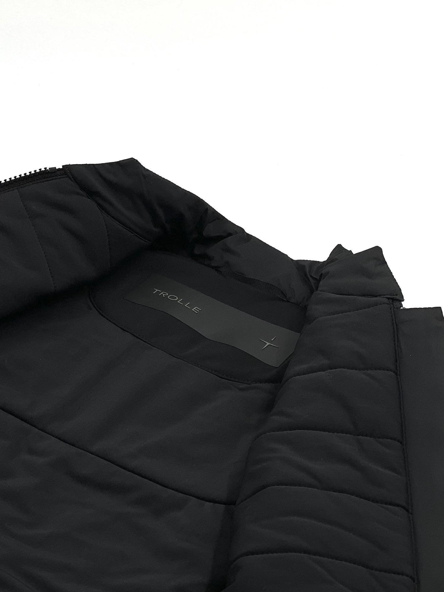 Close-up of a black quilted jacket with a brand logo on a white background