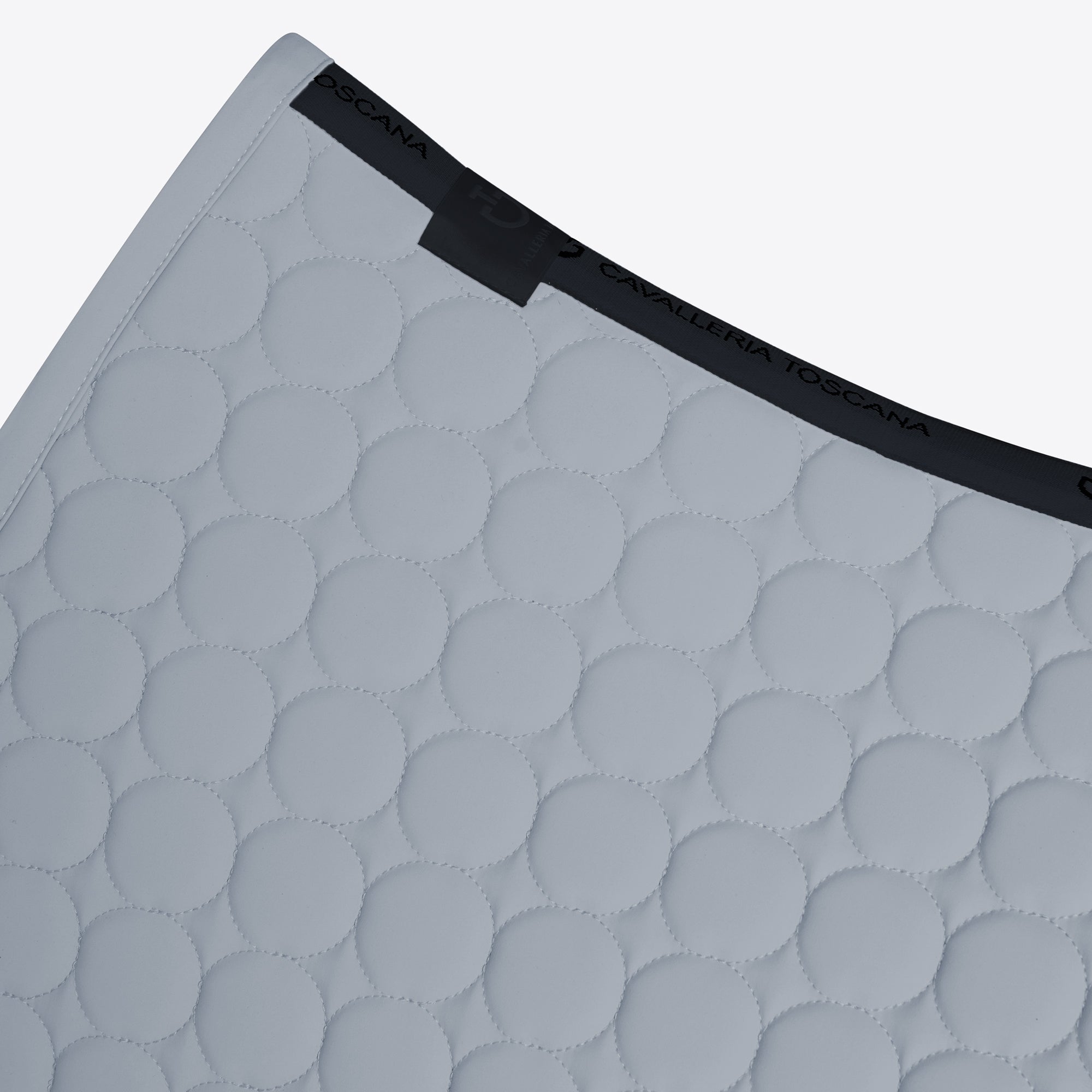 Close-up of a light gray quilted mattress topper with a circular stitched pattern and a black elastic band featuring the brand name &