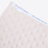 A close-up of a light beige baby blanket featuring a repeating anchor pattern and a white elastic band with the brand name &