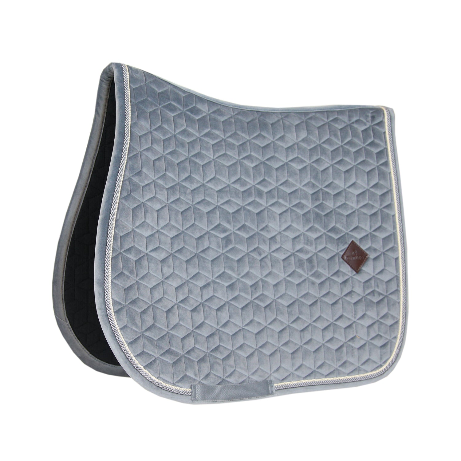 The Saddle Pad Basic Velvet is shaped for jumping and provides excellent cushioning between the horse’s back and the saddle while protecting against friction. It is stylish And classy, with a double twisted piping. This pad has no annoying straps to attach to the saddle, only a nylon strap for the girth. The subtle artificial leather logo is placed in a central,
