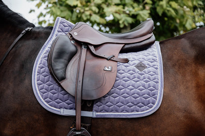 The Saddle Pad Basic Velvet is shaped for jumping and provides excellent cushioning between the horse’s back and the saddle while protecting against friction. It is stylish And classy, with a double twisted piping. This pad has no annoying straps to attach to the saddle, only a nylon strap for the girth. The subtle artificial leather logo is placed in a central,