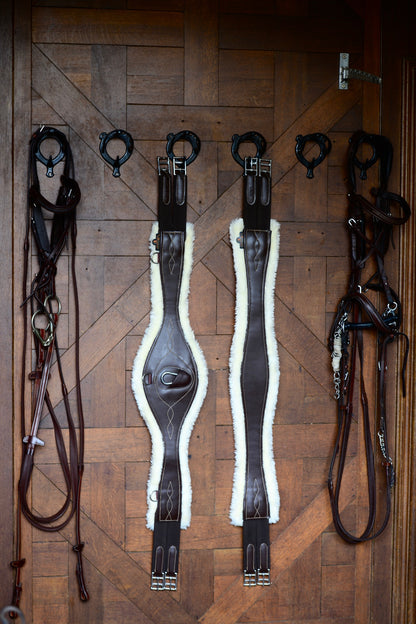 The Kentucky anatomical girth with sheepskin lining. This girth is made from artificial leather, making it softer, more durable and easier to maintain and clean. The faux sheepskin is removable, making it easier to watch and re attaches with strong Velcro.   A silver hope and carabiner is found underneath to attach your martingale, breastplate, draw reigns etc.    The girth is available in black or brown.
