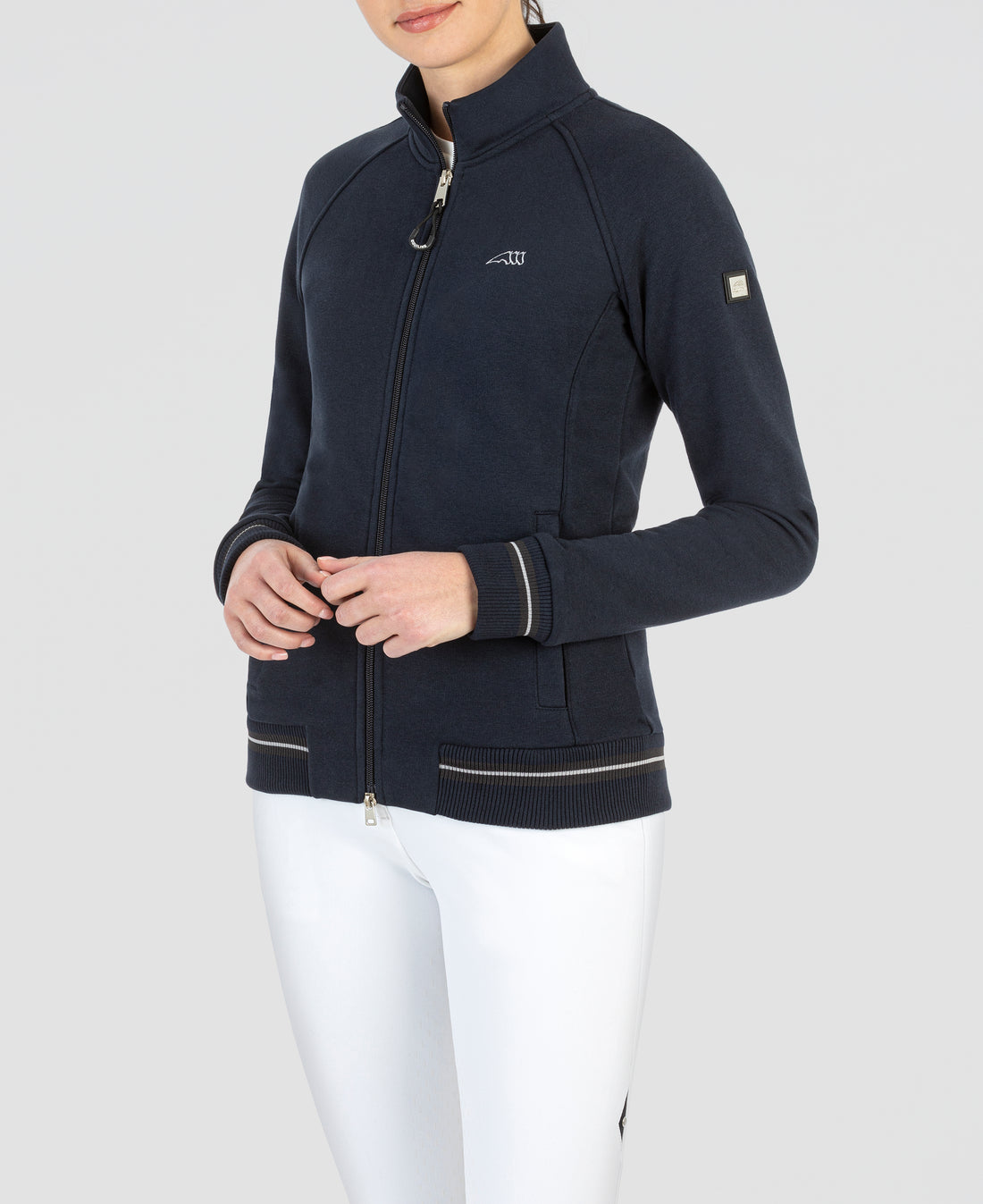 This classic Equiline zip through sweet shirt is a staple piece for any wardrobe. Equiline 3 horse logo in the front with complementing white stripe through the rib hem and logo tab on sleeve. 